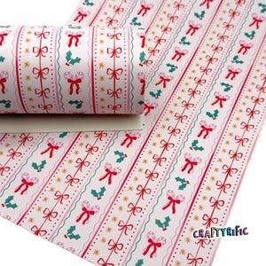 May include: A roll of patterned paper with a repeating Christmas design. The pattern features red bows, candy canes, holly, and gold stars on a white background. The paper has vertical stripes with pink and teal accents.