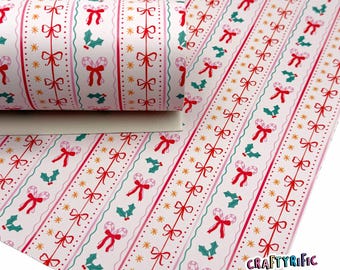 May include: A roll of patterned paper with a repeating Christmas design. The pattern features red bows, candy canes, holly, and gold stars on a white background. The paper has vertical stripes with pink and teal accents.