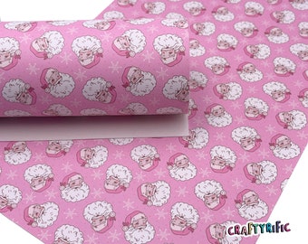 May include: Pink faux leather sheet with a repeating pattern of Santa Claus faces and snowflakes. The background is a light pink color and the Santa Claus faces are white with pink accents. The text "CRAFTYrific" is visible in the bottom right corner of the image.