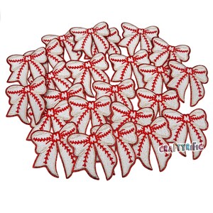 May include: A pile of 20 white and red baseball-themed bow patches. The bows are embroidered with white stitching and red stitching that resembles baseball stitching.
