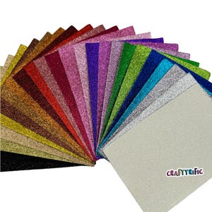 May include: A fan of 20 different colors of glitter cardstock. The cardstock is arranged in a rainbow pattern with the colors ranging from black to white. The cardstock is all the same size and is about 12 inches long. The cardstock is perfect for crafting and scrapbooking.