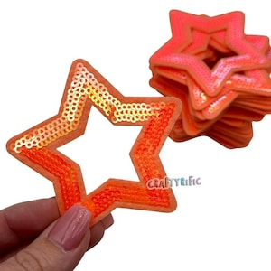 May include: A pack of 10 orange iridescent star-shaped sequins. The sequins are sewn onto a felt backing. The sequins are about 2 inches in diameter.