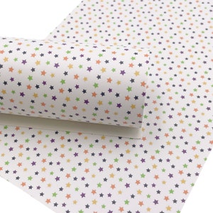 May include: White fabric with a repeating pattern of small, multi-colored stars. The stars are in shades of green, orange, yellow, and purple.