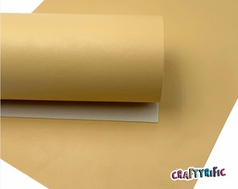 May include: A sheet of light yellow faux leather with a textured surface. The leather is rolled up and the text "CRAFTYRIFIC" is visible in the bottom right corner.