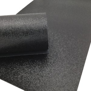 May include: Black glitter fabric with a textured surface. The fabric is rolled up and the glitter is visible.