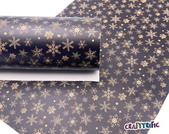 May include: Black faux leather with a gold snowflake pattern. The snowflakes are outlined in a darker gold color. The fabric is rolled up and the text "CRAFTYRIFIC" is visible in the bottom right corner.
