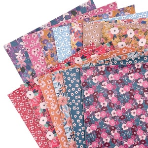 May include: A stack of patterned fabric sheets in various shades of pink, blue, and brown with floral designs. The fabric sheets are arranged in a fan shape.