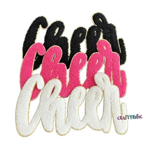 May include: Three layered felt "cheer" signs in black, pink, and white with gold glitter accents. The signs are stacked on top of each other.