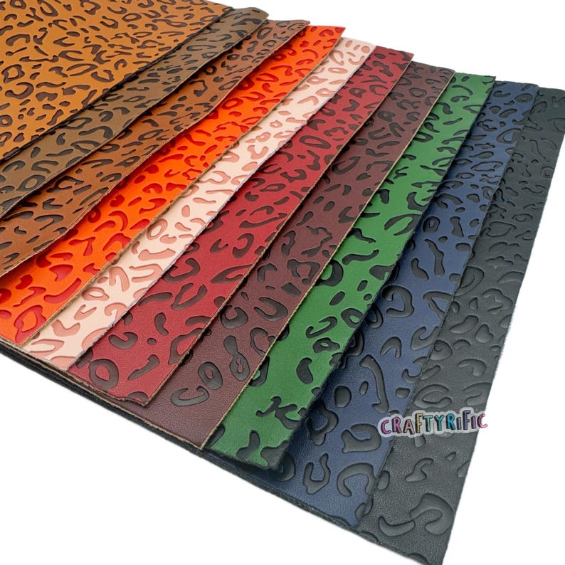 K&ouml;nnte beinhalten: Eine Sammlung von zehn Kunstlederb&ouml;gen in verschiedenen Farben mit einem gepr&auml;gten Leopardenmuster. Die Farben umfassen Braun, Orange, Rosa, Rot, Burgunder, Dunkelgr&uuml;n und Marineblau.
