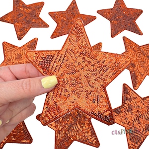 May include: A collection of orange star-shaped sequins. The sequins are sewn together to create a patch that can be used for crafting or decorating.