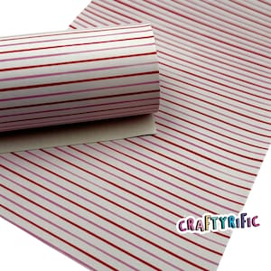 May include: A roll of white material with red and pink horizontal stripes. The material is unrolled on a white surface with the same striped pattern. The word "CRAFTYrific" is printed in a white font with a pink outline.