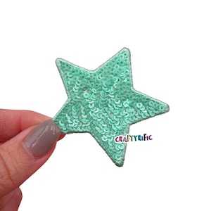 May include: A light green star-shaped patch covered in sequins. The patch is perfect for adding a touch of sparkle to crafts and projects.
