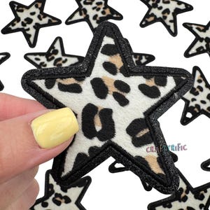 May include: A set of five black and white leopard print star-shaped iron-on patches. The patches have a black outline and are approximately 3 inches in diameter.