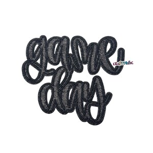 May include: A glittery black "Game Day" cutout in a cursive font. The letters are outlined with a darker black border. The word "Craftyrific" is in the upper right corner in a colorful font.