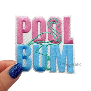 Puede incluir: Parche bordado con las palabras "POOL BUM" en rosa y azul, con un diseño de flamenco turquesa. El parche es rectangular con un fondo blanco y el texto "CRAFTYRIFIC" en la esquina inferior derecha.
