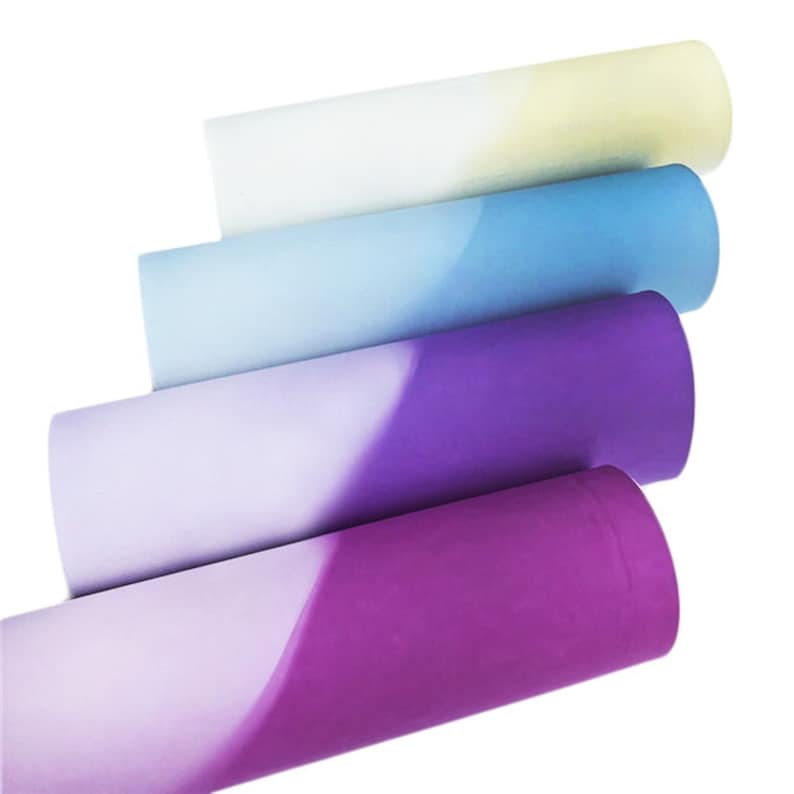 May include: Four rolls of ombre tissue paper in shades of purple, blue, and yellow. The tissue paper is rolled up and the ends are visible.