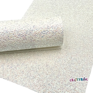 May include: A roll of white glitter fabric with a textured surface. The fabric has a subtle iridescent sheen, reflecting various colors. The CraftyRific logo is visible in the bottom right corner. This material is suitable for crafts and DIY projects.