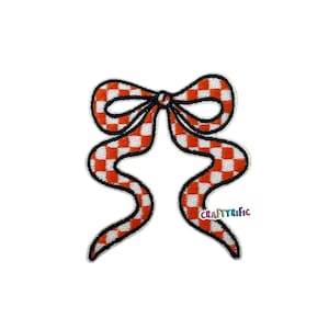 May include: A decorative bow patch with a red and white checkered pattern. The bow has a black outline and a black center knot. The patch is in the shape of a bow with two flowing ribbons. The text "CRAFTYRIFIC" is visible on the lower right ribbon.