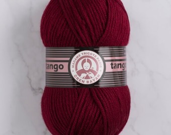 May include: A ball of deep red yarn with a label that reads "Tango" and "Madame Tricote Paris" in black and white text. The label also features a pink circle with a baby wearing a white hat and holding knitting needles.