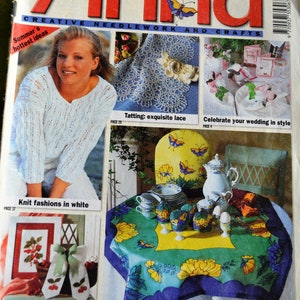 May include: A magazine cover for Anna, a publication about creative needlework and crafts. The cover features a woman wearing a white knitted sweater, a crocheted doily, a table setting with a floral tablecloth, and a variety of embroidery projects. The magazine title is in red and white letters, and the cover text includes "Summer's hottest ideas", "Knit fashions in white", "Tatting: exquisite lace", "Celebrate your wedding in style", "Cherries to embroider", and "Fantastic silk: enchanting table decorating".
