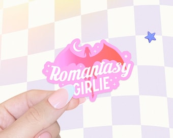 May include: Pink sticker with a pink dragon silhouette and the text "Romantasy Girlie" in a white cursive font.
