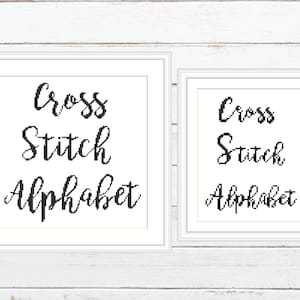 Pode incluir: Duas impressões emolduradas sobre um fundo de madeira branca. As impressões apresentam as palavras "Cross Stitch Alphabet" em escrita preta. As molduras são brancas, com a impressão maior à esquerda e uma versão menor à direita.
