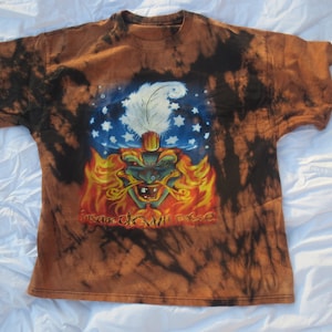 May include: A brown, black, and blue tie-dye t-shirt with a graphic of a jester wearing a hat with stars and a feather. The text "Insane Clown Posse" is printed below the graphic.