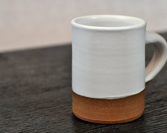 Peut inclure: Une tasse en céramique blanche avec une bordure et une base brunes. La tasse a un design simple et est parfaite pour un usage quotidien.