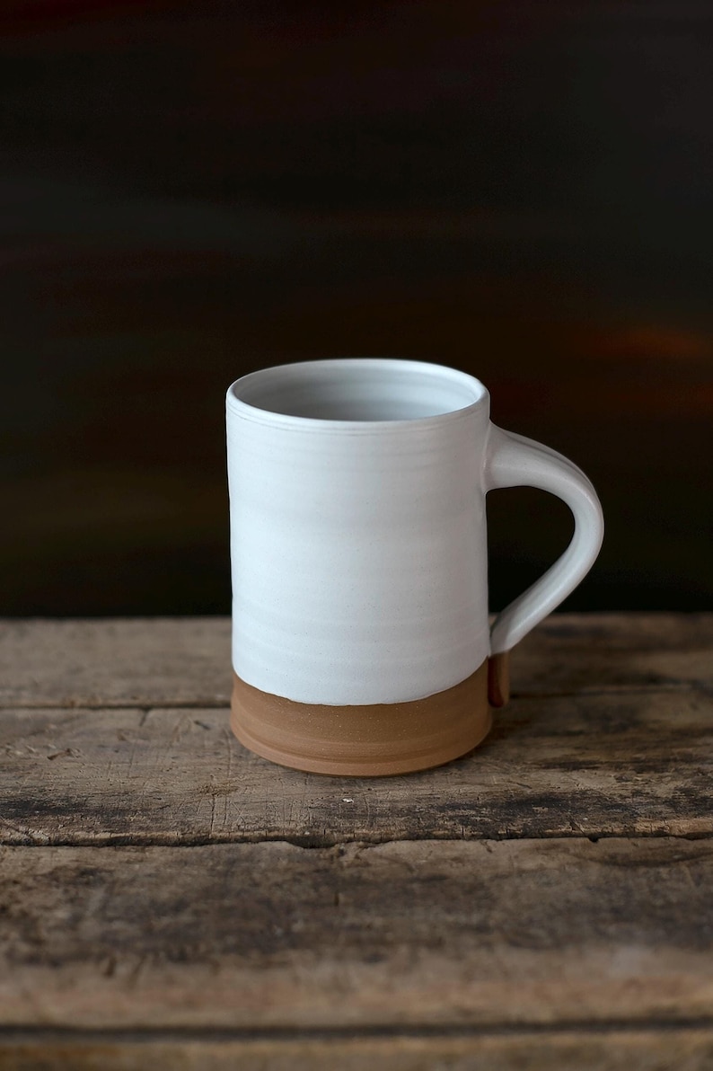 Handmade thrown mug with rustic styling. Each piece is handmade and unique made in America. White glaze and brown clay.