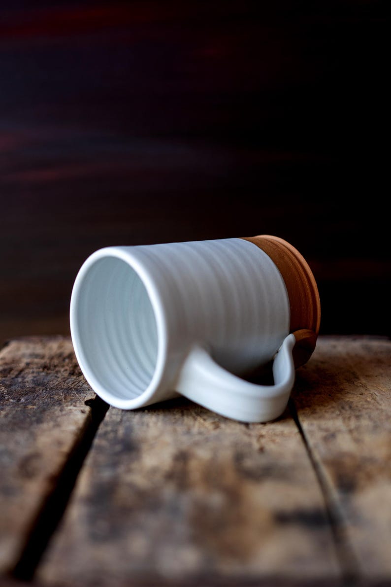 Handmade thrown mug with rustic styling. Each piece is handmade and unique made in America. White glaze and brown clay.