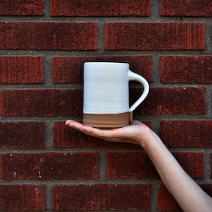 Handmade thrown mug with rustic styling. Each piece is handmade and unique made in America. White glaze and brown clay.