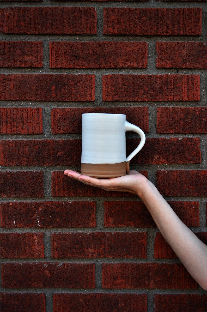 Handmade thrown mug with rustic styling. Each piece is handmade and unique made in America. White glaze and brown clay.