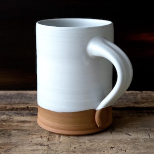 Handmade thrown mug with rustic styling. Each piece is handmade and unique made in America. White glaze and brown clay.