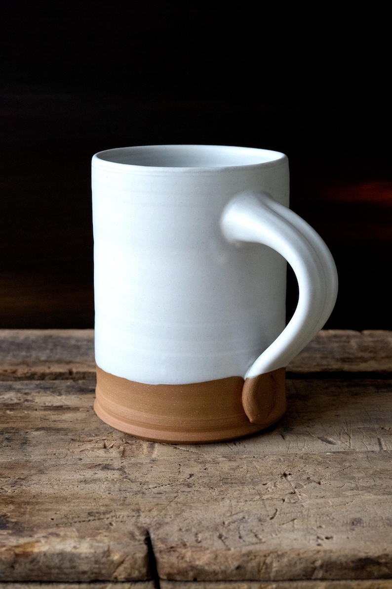 Handmade thrown mug with rustic styling. Each piece is handmade and unique made in America. White glaze and brown clay.