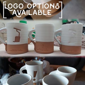 May include: A collection of ceramic mugs featuring various logo options. The mugs are white with a brown band around the base. The logos include a pair of speech bubbles, a stylised letter "F", and an exclamation mark with a star.