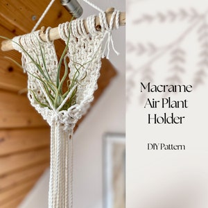 May include: A white macrame air plant holder with a green air plant inside. The holder is hanging from a wooden branch. The text "Macrame Air Plant Holder DIY Pattern" is written in black text on a white background.