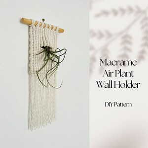 May include: White macrame air plant holder with a wooden dowel at the top and a green air plant inside. The text "Macrame Air Plant Wall Holder DIY Pattern" is below the holder.