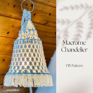 以下が含まれることがあります： 白いタッセルフリンジが付いた薄い青色のマクラメシャンデリア。シャンデリアは木製の羽目板のある天井から吊り下げられています。画像には「マクラメシャンデリアDIYパターン」というテキストが表示されています。