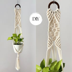 Peut inclure: Une suspension pour plante en macramé faite de corde blanc cassé avec un anneau en bois brun foncé en haut et des motifs noués complexes. La suspension soutient un pot blanc contenant une plante verte. Le texte DIY est visible dans un cercle blanc.