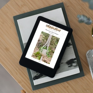 May include: A digital tablet displaying a printable macrame plant hanger pattern from White Owl Knot. The pattern includes instructions for a macrame plant hanger with a white cord and a potted plant.