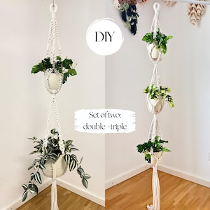 Op de afbeelding: Een set van twee off-white macramé plantenhangers met een ontwerp met twee en drie niveaus. Elke hanger is gemaakt van geknoopt koord en bevat witte potten met groene planten. De tekst DIY en SET OF TWO: double + triple is zichtbaar.