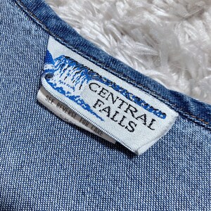 May include: Close-up of a denim garment with a white tag. The tag features the text "CENTRAL FALLS" in a bold, sans-serif font, with a blue and white graphic. The tag also includes the text "SEE REVERSE FOR CARE".