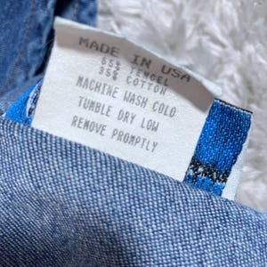May include: A close-up shot of a clothing label with the text "MADE IN USA". The label details the fabric content as 55% TENCEL and 35% COTTON. Washing instructions include "MACHINE WASH COLD" and "TUMBLE DRY LOW".