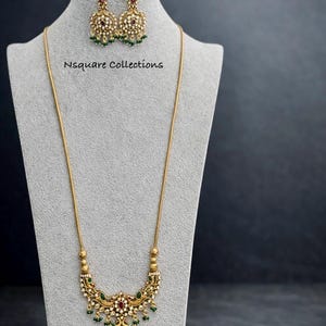 Pode incluir: Uma caneca de cerâmica branca com uma alça preta e o texto "But First, Coffee" em negrito preto. A caneca está sobre um fundo desfocado, sugerindo um ambiente acolhedor.