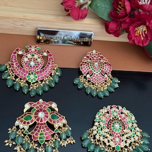 May include: Four ornate gold-tone earrings featuring intricate filigree patterns inlaid with vibrant pink and green stones. Each piece is accented with dangling light green teardrop beads and small white pearls, arranged in symmetrical floral and bird motifs.