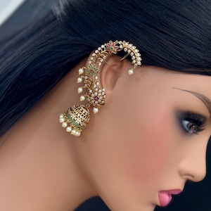 Pode incluir: Uma pulseira de orelha dourada com intrincados desenhos florais e de folhas, adornada com pequenas pedras preciosas coloridas e pérolas falsas. A pulseira curva-se ao longo da orelha, com um elemento pendurado em forma de sino.