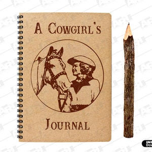 May include: A spiral-bound journal with a tan cover featuring a dark brown circular graphic of a horse and a person wearing a hat, with the text A COWGIRL'S JOURNAL printed on the front, accompanied by a rustic pencil made from a tree branch.