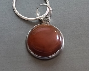 May include: A silver chain necklace with a round pendant featuring a brown gemstone.
