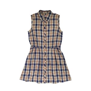 Op de afbeelding: Een mouwloze geruite jurk met een knoopsluiting aan de voorkant en een getailleerde taille. De jurk is bruin, blauw en wit.