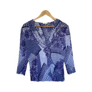 May include: A purple and blue patterned blouse with a V-neck and 3/4 sleeves.